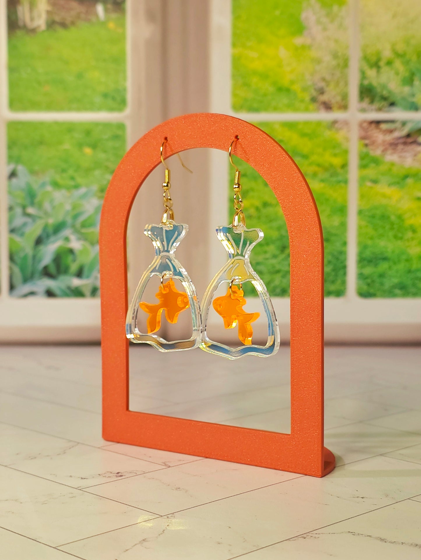 Handmade goldfish bag earrings featuring iridescent acrylic fish bags with translucent orange goldfish charms and hypoallergenic stainless steel ear wires.