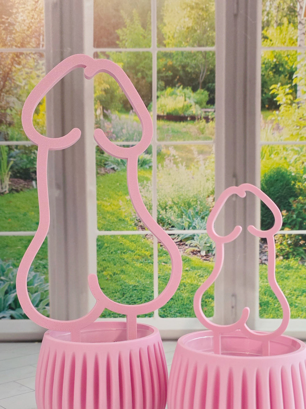 Pink decorative Rise and Shine plant trellis in a ribbed pink planter near a bright window