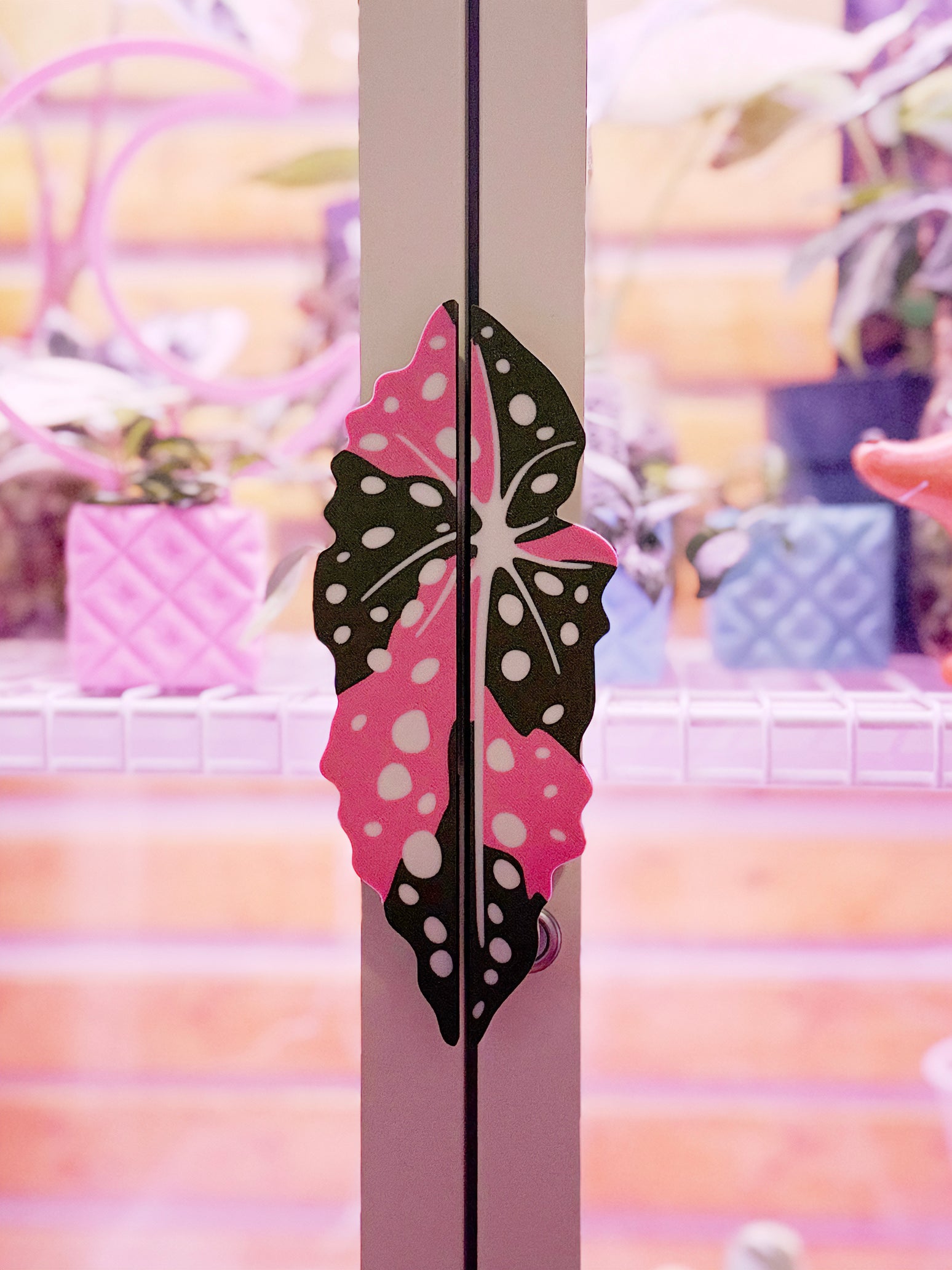 Variegated Begonia maculata cabinet handle covers with pink and green spotted leaf design on a white milsbo tall cabinet.